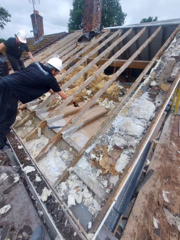 Roofers stripping a roof back to the rafters