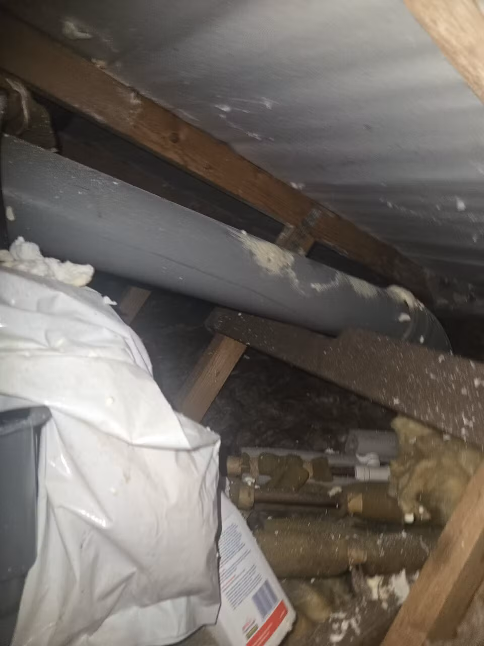 Bagged waste and loose insulation in the loft during spray foam removal