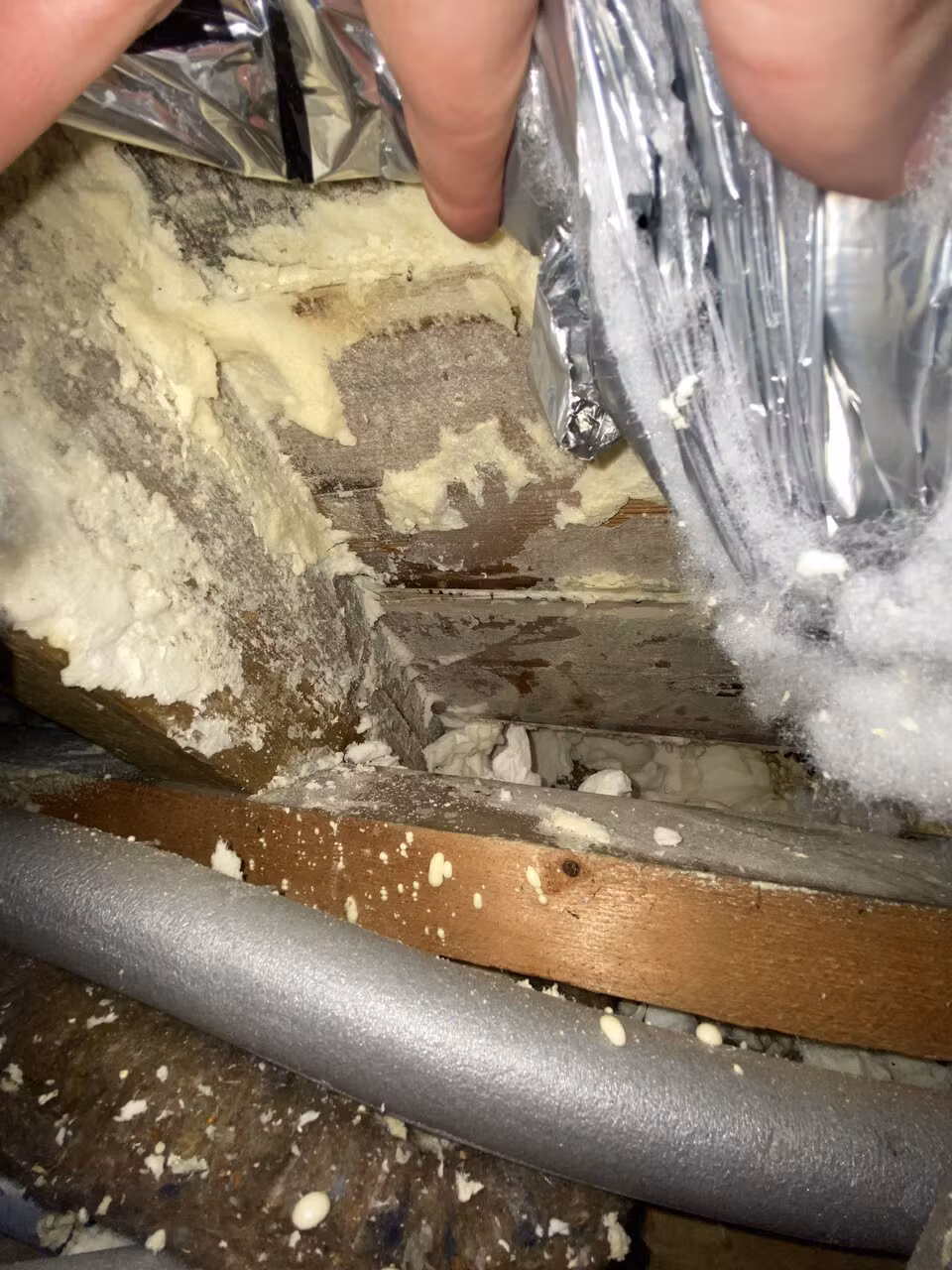 Spray foam residue left between the rafters after a previous removal attempt