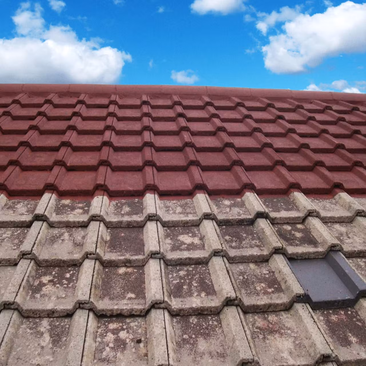 Tiled roof partly coated in red beside uncoated tiles